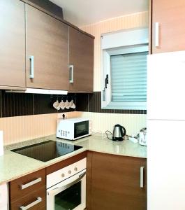 a kitchen with wooden cabinets and a microwave at Punta Prima Pleamar in Orihuela Costa