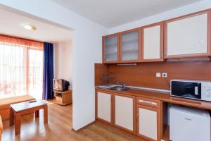 a kitchen with wooden cabinets and a living room at Хотел Лагуна in Chernomorets