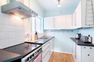 a kitchen with white cabinets and a sink and a stove at The Location - TV in Every Bedroom! in Swansea