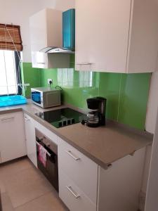 a kitchen with green and white cabinets and a counter top at Ibiz Tourist Residence 2 in Mahébourg
