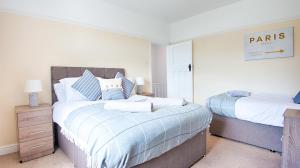 a bedroom with two beds with blue and white sheets at Off Road parking, Garden, TV in Every Room in Swansea