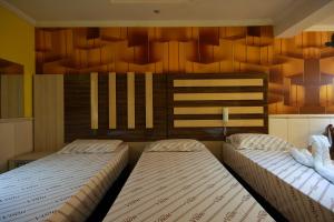 two beds in a bedroom with wooden walls at Motel Vison (Próximo GRU Aeroporto) in Guarulhos