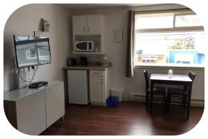 a living room with a table and a kitchen with a television at Shoreline Suites in Digby