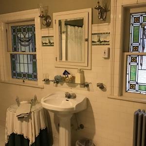Brookview Manor Inn في Canadensis: حوض أبيض في الحمام مع نوافذ من الزجاج الملون