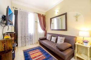 a living room with a brown couch and a mirror at aloha apartments in Marsalforn