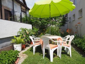 een tafel en stoelen met een groene parasol bij Hoffman Apartment in Balatonszárszó