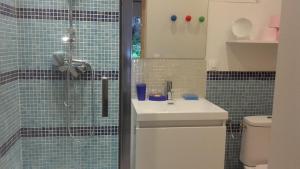 ein Badezimmer mit einem Waschbecken und einer Dusche mit blauen Fliesen in der Unterkunft La Polaris in Angerville-lʼOrcher