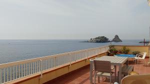 een balkon met een tafel en stoelen en de oceaan bij casa Ciclopi in Acitrezza