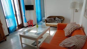 un soggiorno con divano arancione e tavolo in vetro di casa Ciclopi ad Acitrezza