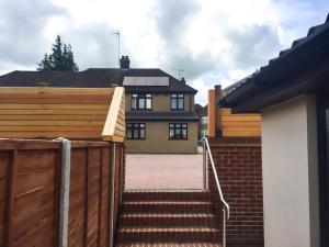 a house with a wooden fence and stairs in front at Cherish End Guest House in Dunstable