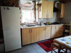 a kitchen with wooden cabinets and a white refrigerator at Mūsų kiemas in Pervalka