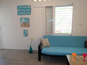 ein Wohnzimmer mit einem blauen Sofa und einem Fenster in der Unterkunft Simberts Apartments in Maya Beach