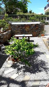 un banco de picnic en un jardín con una pared de piedra en Apartment with Sea View..., en Samos