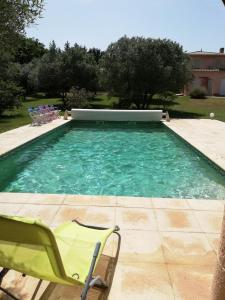 una piscina con una silla verde, una mesa y sillas en Au Sabluline chambres d'hôtes gîtes, en Draguignan