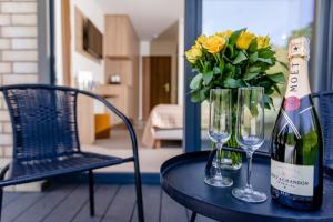 a table with a bottle of wine and a vase of flowers at Matusz Apartamenty in Pobierowo