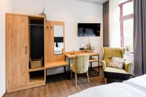 um quarto com uma secretária, uma cama, uma secretária e cadeiras em 360 Grad Hotel & Bar em Leer