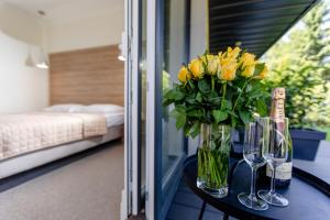 einen Tisch mit einer Vase gelber Blumen und Weingläsern in der Unterkunft Matusz Apartamenty in Pobierowo