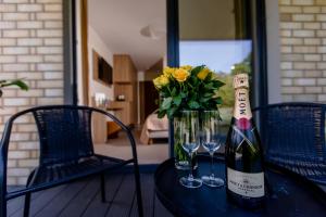 Matusz Apartamenty في بوبيروفو: زجاجة من النبيذ و إناء من الزهور على طاولة