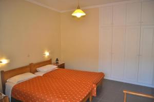 a bedroom with a bed with an orange comforter at Holiday Studio Apartments yannis on Agios Gordios beach in Corfu in Agios Gordios