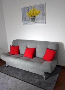 un sofá con 3 almohadas rojas en la sala de estar en Apartament H&P Silver en Varsovia