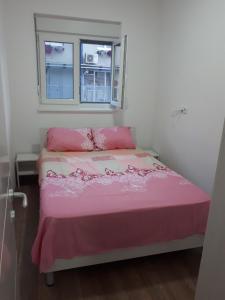 een slaapkamer met een roze bed en een raam bij Aqua park apartmani in Jagodina