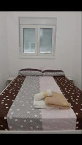 een slaapkamer met een bed met een deken en een raam bij Aqua park apartmani in Jagodina
