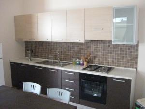 a kitchen with white cabinets and a sink and a stove at Apartment Eutime- in Locri