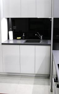 una cocina con armarios blancos y fregadero en Apartament H&P Silver en Varsovia