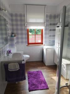 a bathroom with a white sink and a purple rug at Wikno Dom wakacyjny in Wikno