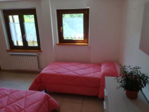 a room with a bed and a couch and two windows at Appartamento Lo Slittone in Abetone