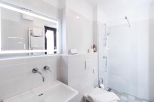 a white bathroom with a sink and a shower at Second Life in Piran - Hotel Zala Piran in Piran