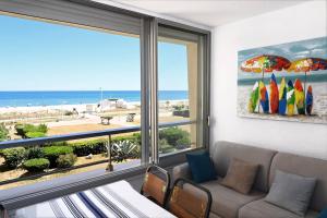 a living room with a couch and a view of the beach at Le Long Beach - Leconfortalaplage in Le Barcarès
