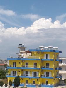 a yellow building with blue balconies on top of it at Amelia Apartments in Ksamil