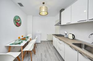 a kitchen with white cabinets and a table and chairs at New Apartment Explanada in Alicante +57 photos