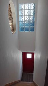 un couloir avec une porte rouge et une fenêtre dans l'établissement Azoka by the Sea- Centro Histórico de Peniche, à Peniche