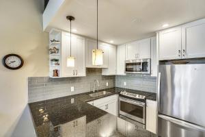 a kitchen with white cabinets and a stainless steel refrigerator at Alea Condo in Kahuku