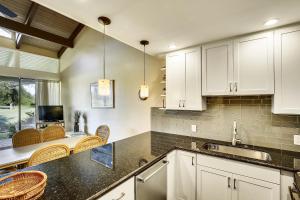 a kitchen with white cabinets and a table with chairs at Alea Condo in Kahuku
