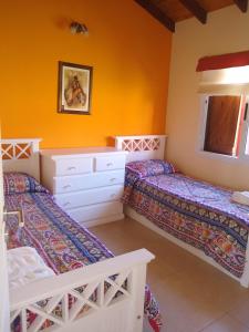 2 camas en una habitación con paredes de color naranja en Las Calandrias en San Clemente del Tuyú