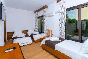 a hotel room with three beds and a window at Kabasakal Otel in Çeşme +23 photos