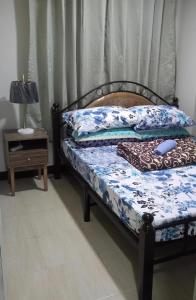 ein Schlafzimmer mit einem Bett und einem Nachttisch mit einem Tisch in der Unterkunft Baguio Central Apartment by Goshenland in Baguio City