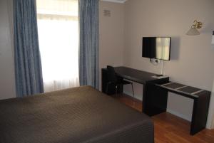 1 dormitorio con cama, escritorio y ventana en Airlie House Motor Inn, en Scone