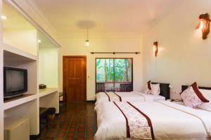 a hotel room with three beds and a television at La Niche D'angkor Boutique Hotel in Siem Reap