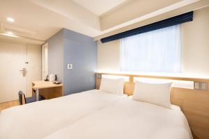 a bedroom with a large white bed with a window at karaksa hotel TOKYO STATION in Tokyo
