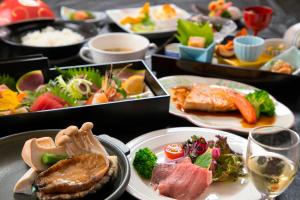 une table avec plusieurs plateaux de nourriture sur les assiettes dans l'établissement Kesennuma Plaza Hotel, à Kesennuma