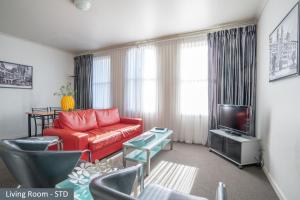 a living room with a red couch and a tv at Clocktower Apartment Hotel in Melbourne