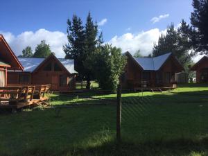 una valla frente a un grupo de casas en Cabañas Huelemu Pucón, en Pucón