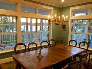 a dining room with a wooden table and chairs and windows at Swanendele Inn in Ridge