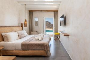 a bedroom with a bed and a view of a pool at Panormos Village Hotel in Mykonos