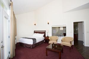 a hotel room with a bed and two chairs and a table at Shiraz Villa in Osoyoos