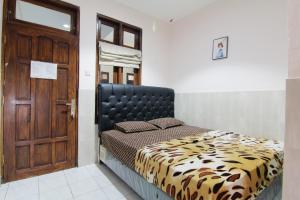1 dormitorio con 1 cama con cabecero negro y puerta en Wanderlust Homestay, en Yogyakarta